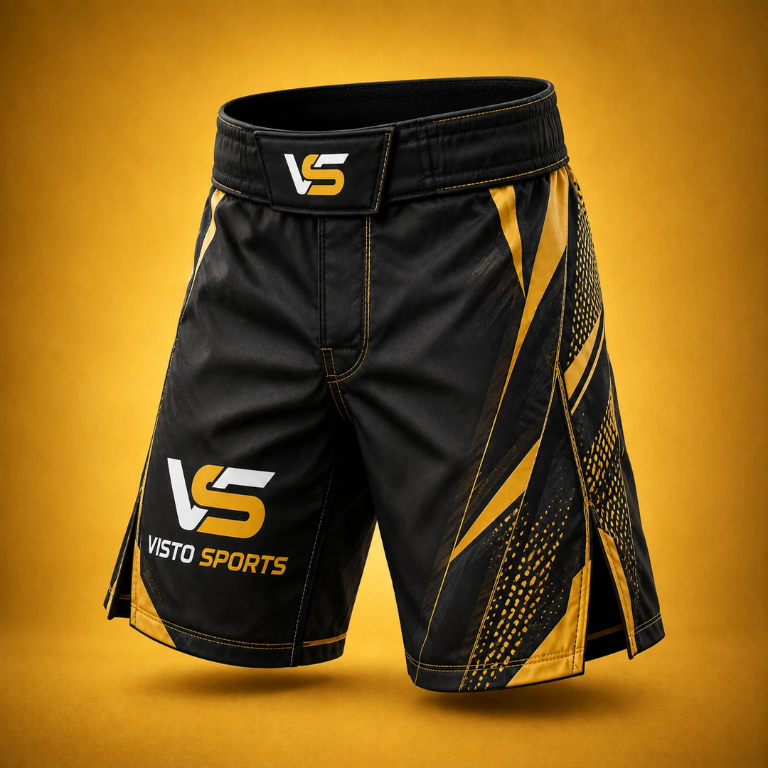 Premium black and gold Visto Sports fight shorts with reinforced waistband, side vents, athletic graphics, and branded detailing on a warm golden studio background.
